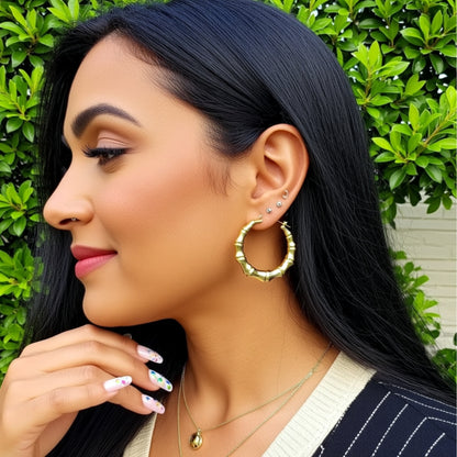 Woman wearing gold hoop earrings with a green leafy background