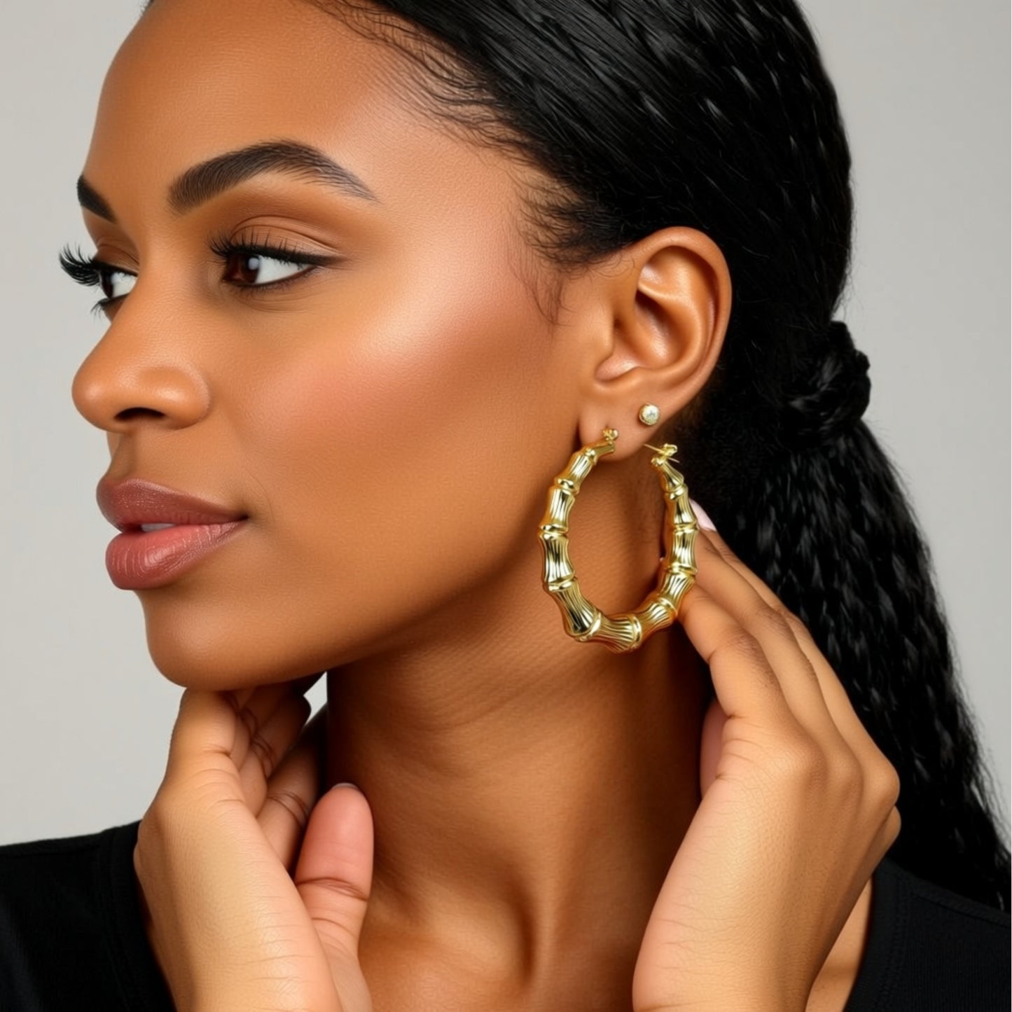 Woman wearing gold hoop earrings with a neutral background