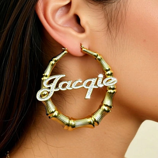 Gold hoop earring with 'Jacquie' engraving worn by a person.