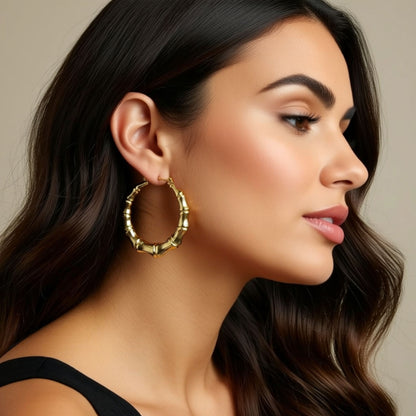 Woman wearing gold hoop earrings with a neutral background