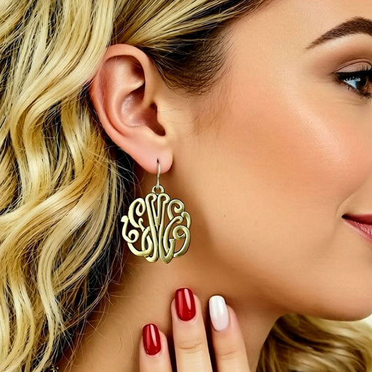 Close-up of a woman wearing a gold monogram earring with a blurred background