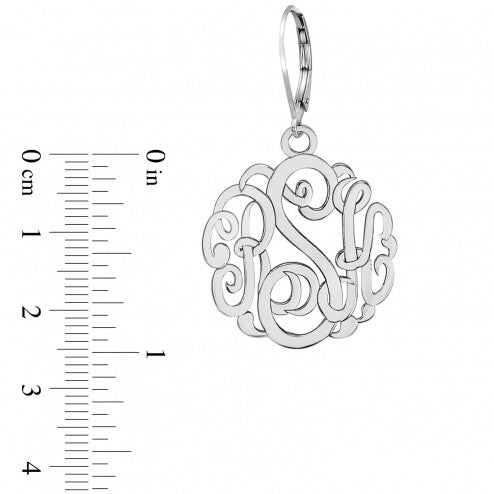 Silver monogram pendant with a ruler for scale on a white background